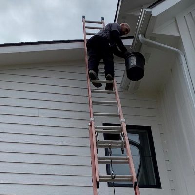 gutter cleaning company employee on ladder cleaning gutters clarksville mi